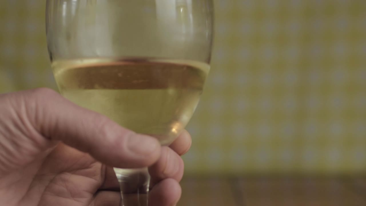 Hand holding glass of white wine close up shot