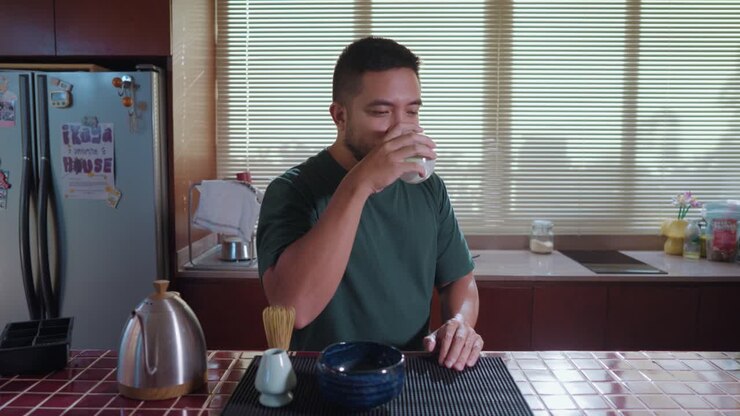 Man enjoying matcha tea ceremony in kitchen