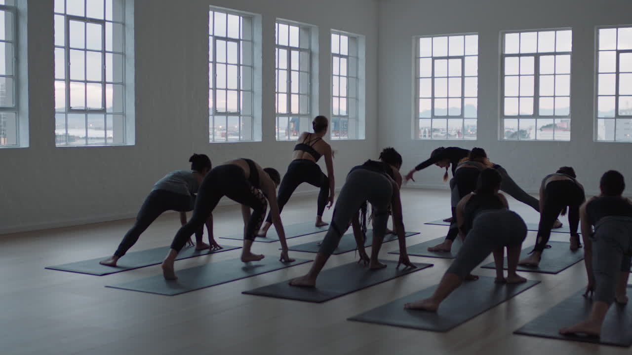전사 포즈를 연습하는 다인종 여성들의 요가 수업 그룹은 일출 때 피트니스 스튜디오에서 건강한 생활 방식을 즐기고 있습니다.