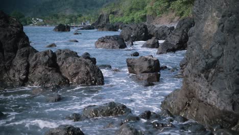 波浪撞擊岩石,背景是熱帶海岸線