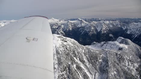 View-of-Light-Airplane-Wingtip-Flying-Over-a-Snowy-MountainLandscape