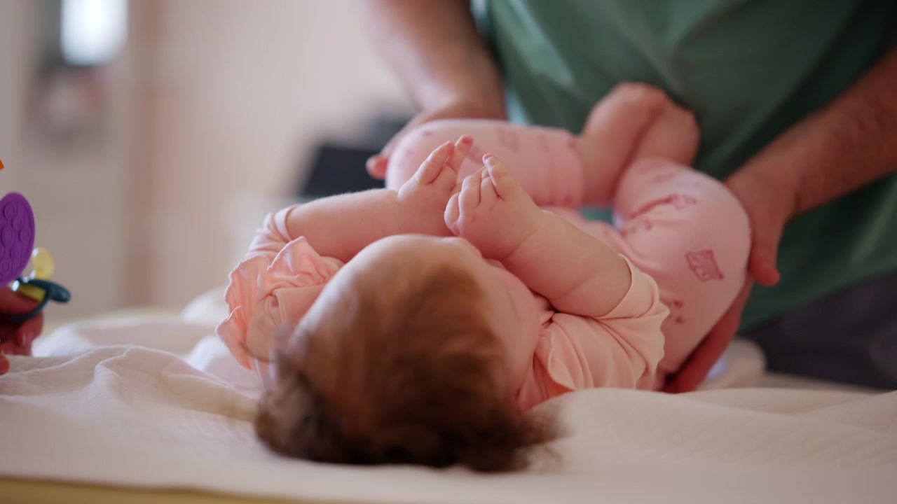 Un bambino giace comodamente mentre guarda un giocattolo colorato e fa esercizi di mobilità con un assistente.