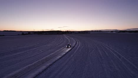 Aerial-View-Driving-Car-At-Snow-Covered-Road-In-Snowy-Winter-Landscape