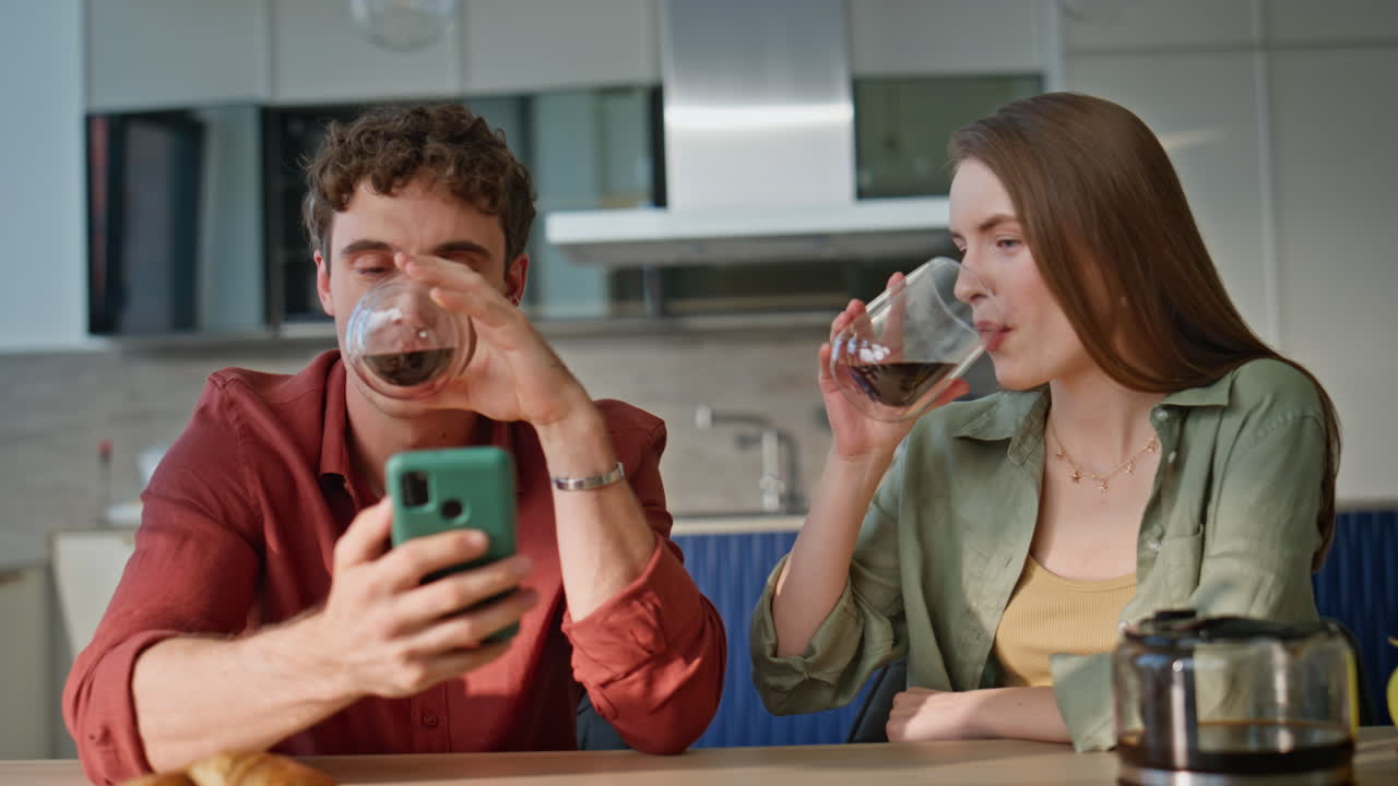 Cheerful spouses enjoy coffee at home morning looking cellphone closeup
