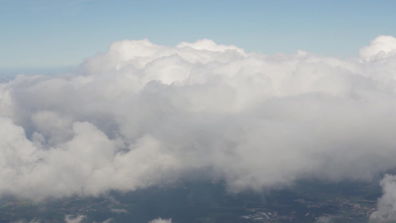 Nubes llenan el cielo desde la vista de un avión. Se ve un cielo azul claro rodeando las nubes blancas. La aeronave está a gran altitud. No se ven puntos de referencia visibles debajo de las nubes
