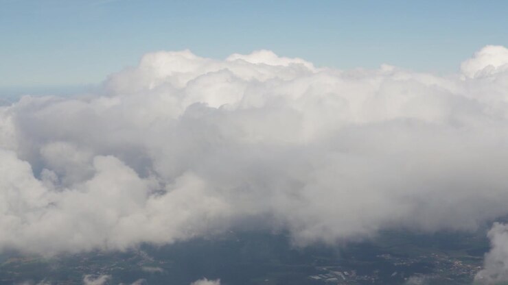 Nubes llenan el cielo desde la vista de un avión. Se ve un cielo azul claro rodeando las nubes blancas. La aeronave está a gran altitud. No se ven puntos de referencia visibles debajo de las nubes