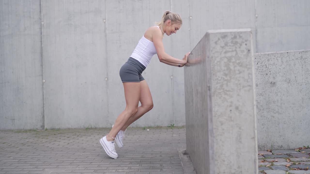 콘크리트 벽 에 맞서 다리 운동 을 하는 여자