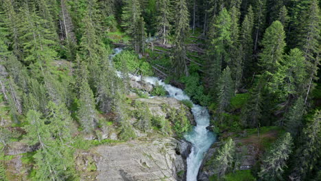 cascate del rutor waterfall flowing through a lush green forest, aerial view