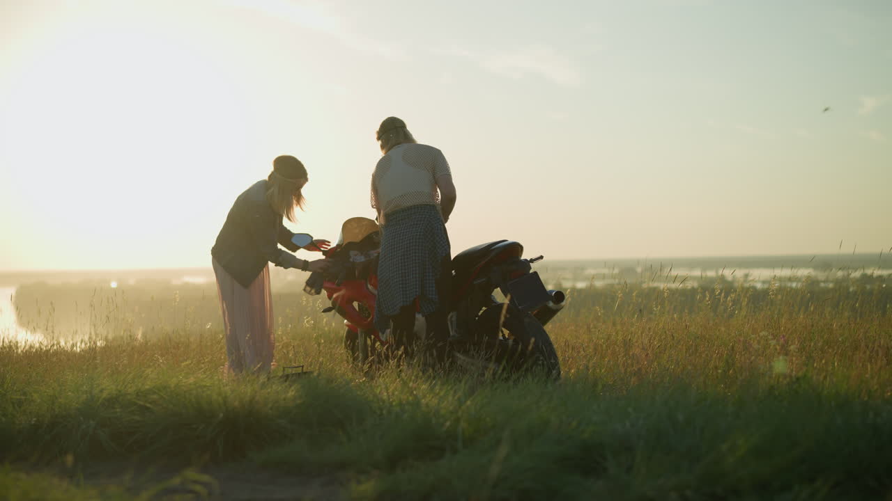 두 자매는 빛에 따뜻한 빛을 비추며 열린 잔디에서 전력 자전거를 철저히 청소하고 있습니다.