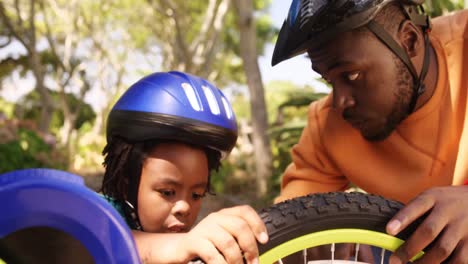 el padre está ayudando a su hijo a reparar la bicicleta