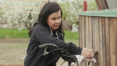 mujer europea limpiando el manillar de una bicicleta con un paño