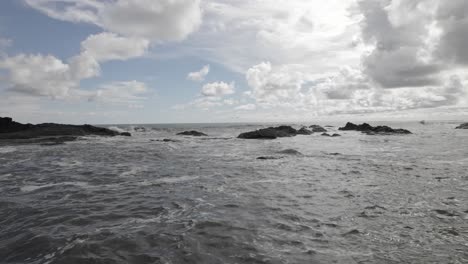 aerial truck left of sea waves near rocky shore on a cloudy day in dominicalito beach, costa rica