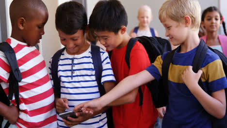 niños de la escuela usando teléfonos móviles en el pasillo