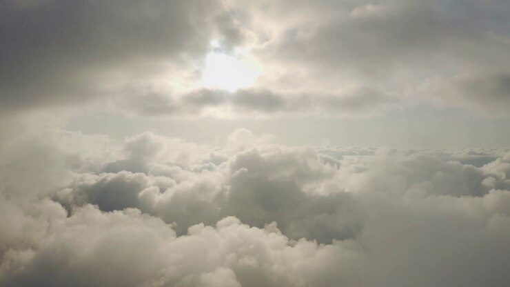 Moving camera revealing central cloud mass billowing above cloud deck, exposing sun glow and rays
