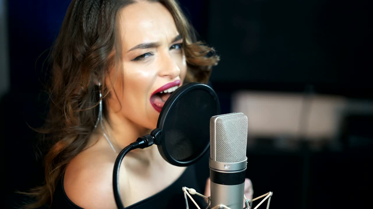 Female singer recording a song in music studio.