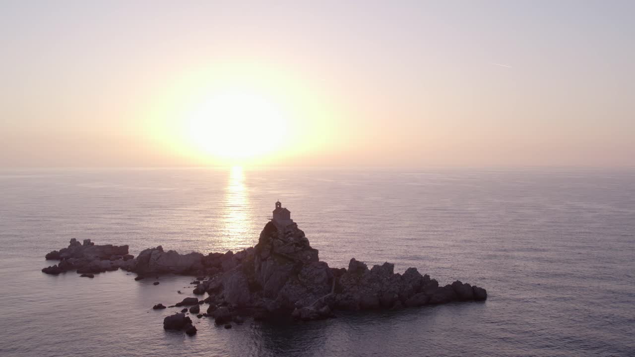 Vista aérea da Igreja de St. Nedjelja em ilha ao pôr do sol no mar Mediterrâneo em Petrovac, Montenegro, com iluminação deslumbrante do pôr do sol, atmosfera calma, imagens de drone de alta qualidade destacando a beleza natural