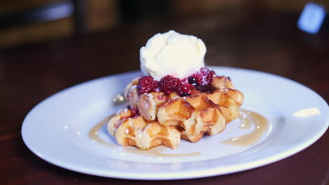 delicious waffle with maple syrup, thickened cream and berry compote