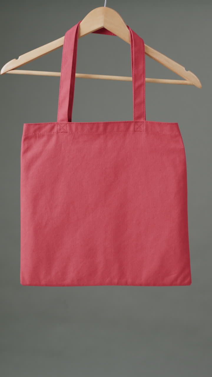 Vertical video of hanger with red canvas bag and copy space on grey background