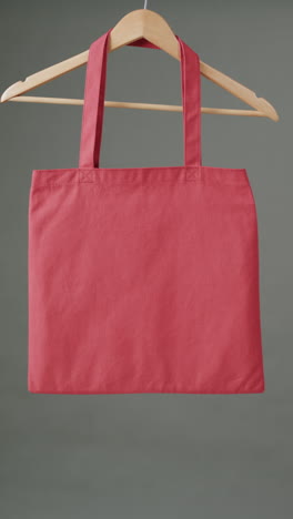 vertical video of hanger with red canvas bag and copy space on grey background