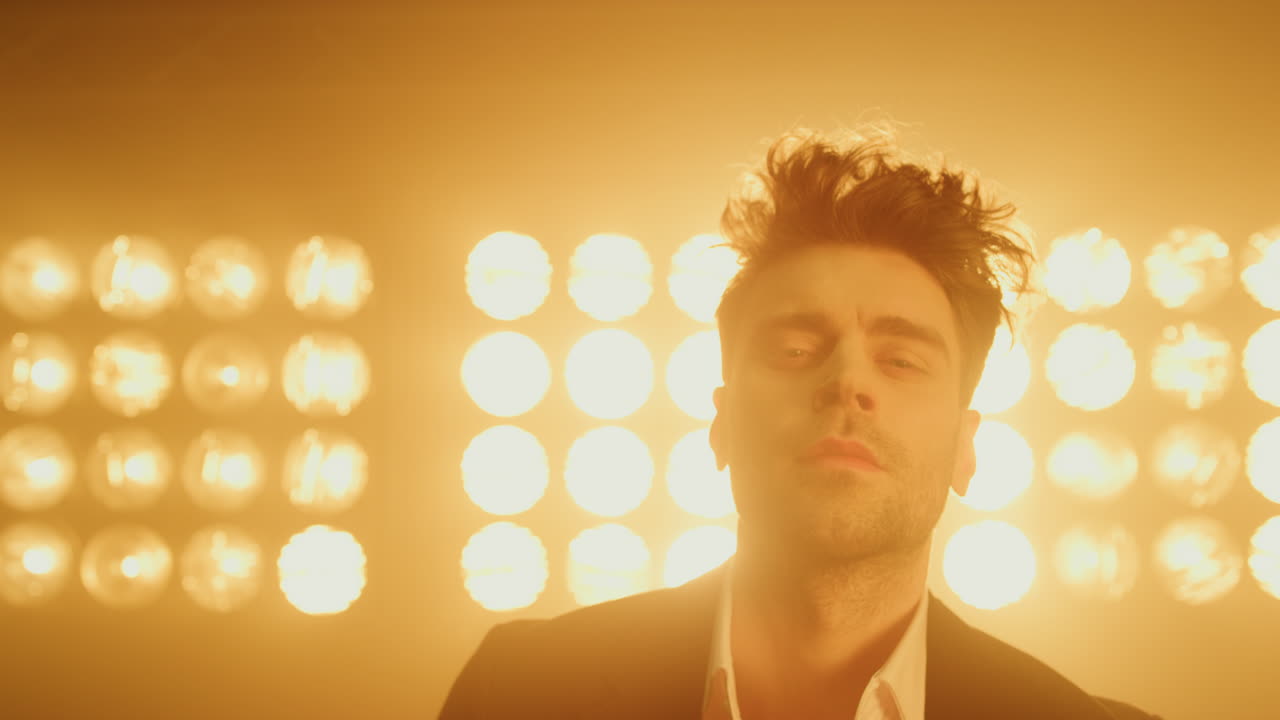 스타일리시한 헤어스타일로 포즈를 취하는 젊은 남성 모델이 스튜디오 스포트라이트에서 카메라를 찾고 있습니다.