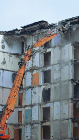 demolition of old residential building. destroying old concrete building using mechanical arm of bulldozer on construction site.