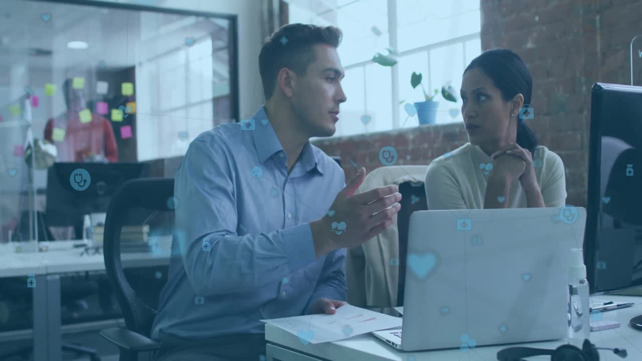Colleagues shifting printed report, pointing chart elements on laptop during business discussion