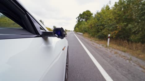 white car on the highway. close-up part of audi car moving on the road at daytime. button on the mirror of the car blinking while electic car is driving.