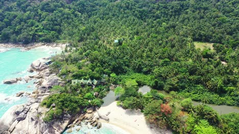 Beautiful-hills-with-green-trees-forest-and-palm-trees-on-shore-of-tropical-island-with-peaceful-exotic-beach-washed-by-turquoise-lagoon,-Thailand