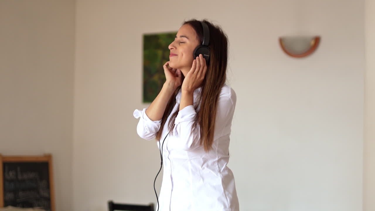 cámara lenta de una joven caucásica sexy bailando sola mientras escucha música con auriculares en casa