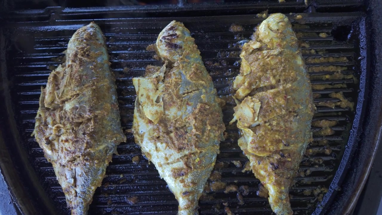 Pesce intero condito al barbecue sulla griglia. Primo piano.