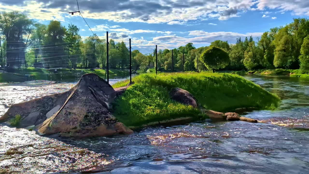Rocky islet and Gauja river current under blue sky in forest area in Valmiera, Latvia
