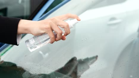 cleaning a car window with spray