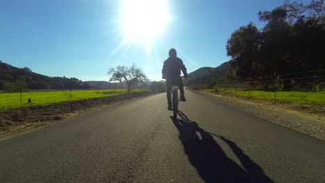 A-man-rides-a-motorized-bicycle-through-the-countryside-on-a-two-lane-road-2