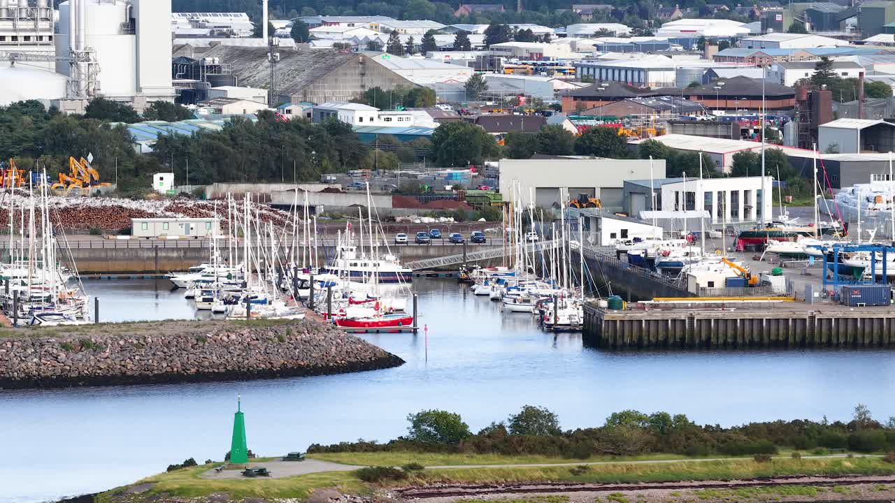 Daytime panoramic camera movement reveals marina, yachts, industrial port, and cityscape in Dundee, Scotland