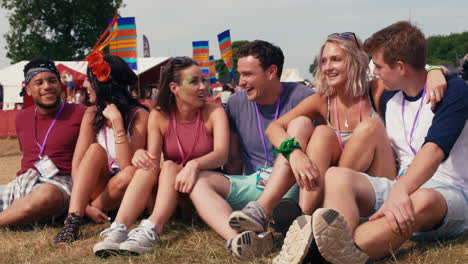 amigos sentados en la hierba viendo un concierto en un festival de música