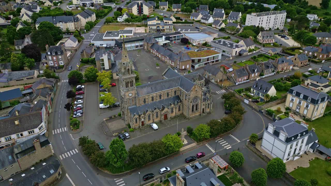 Eglise Saint-Sauveur in town of Plancoet, Brittany, church architecture, surrounding streets, and residential buildings, France. Aerial tilt-up