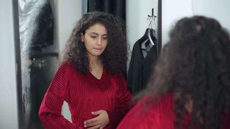 young woman trying on a red dress in a fitting room