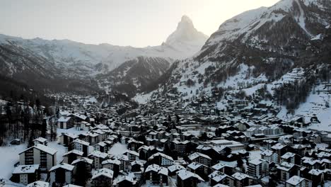 Sobrevuelo-Aéreo-Sobre-Los-Tejados-De-Zermatt-Durante-Un-Atardecer-De-Invierno