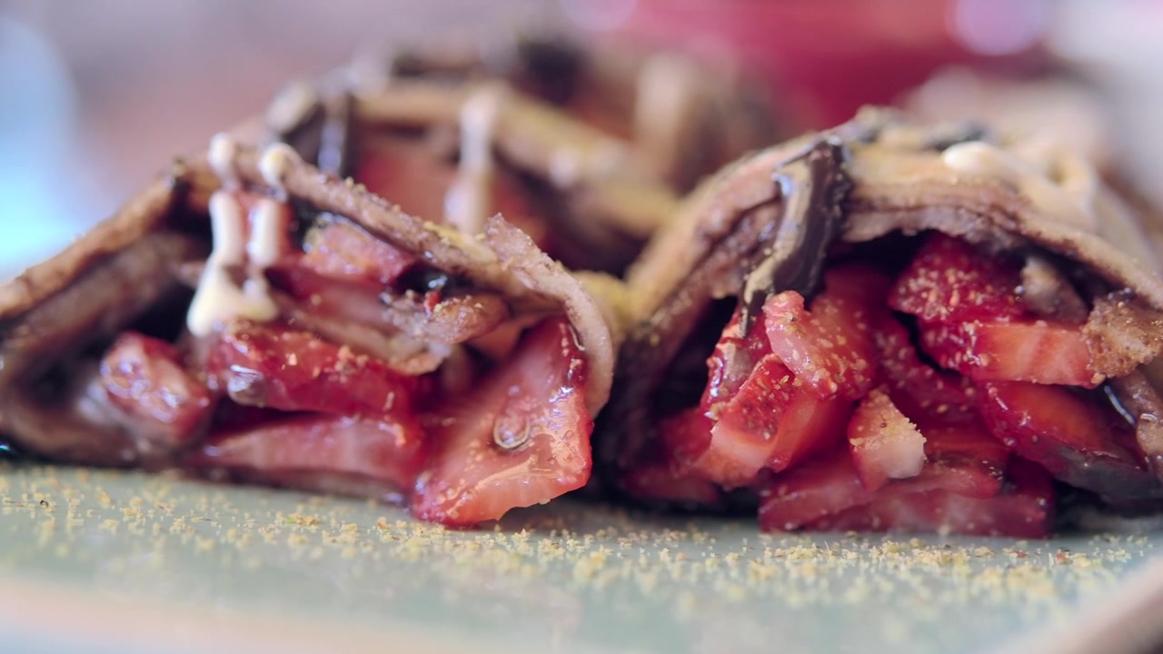 Primo piano di deliziose crepes al cioccolato ripiene di fragole fresche a fette