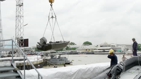 royal thai navy staff deploying speedboats using a crane to be used for patrolling the waters and banks of chao phraya river, in bangkok, thailand.