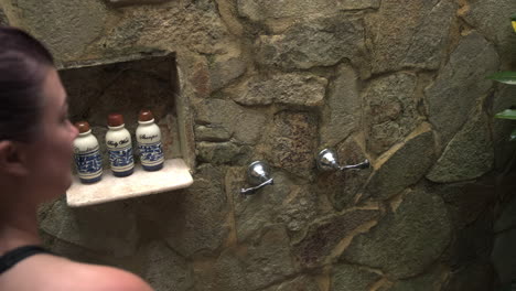 mujer enciende una ducha al aire libre y siente el agua