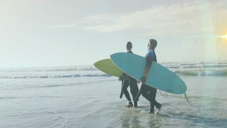 animation of light spots over senior african american couple with surfboards on sunny beach