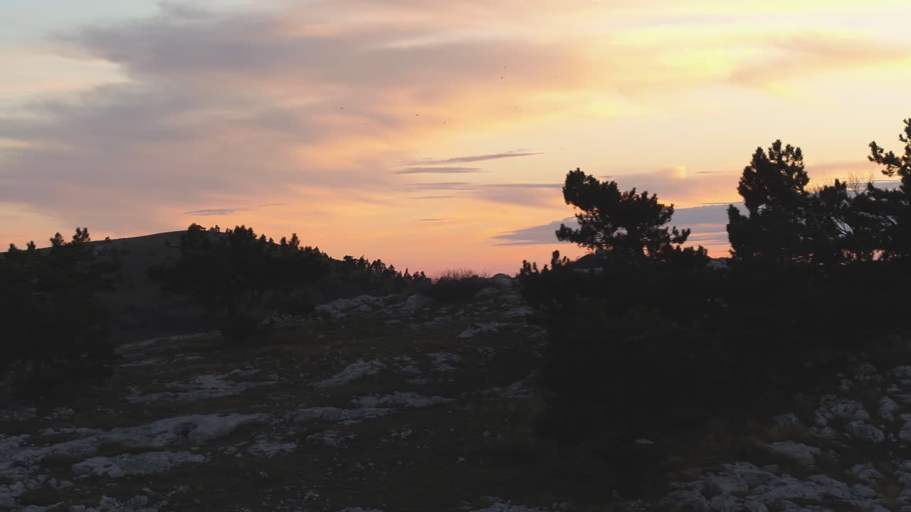 puesta de sol sobre los picos de las montañas con árboles de silueta