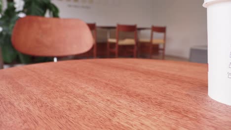 a woman is sitting at a table in a cafe, holding her cell phone.