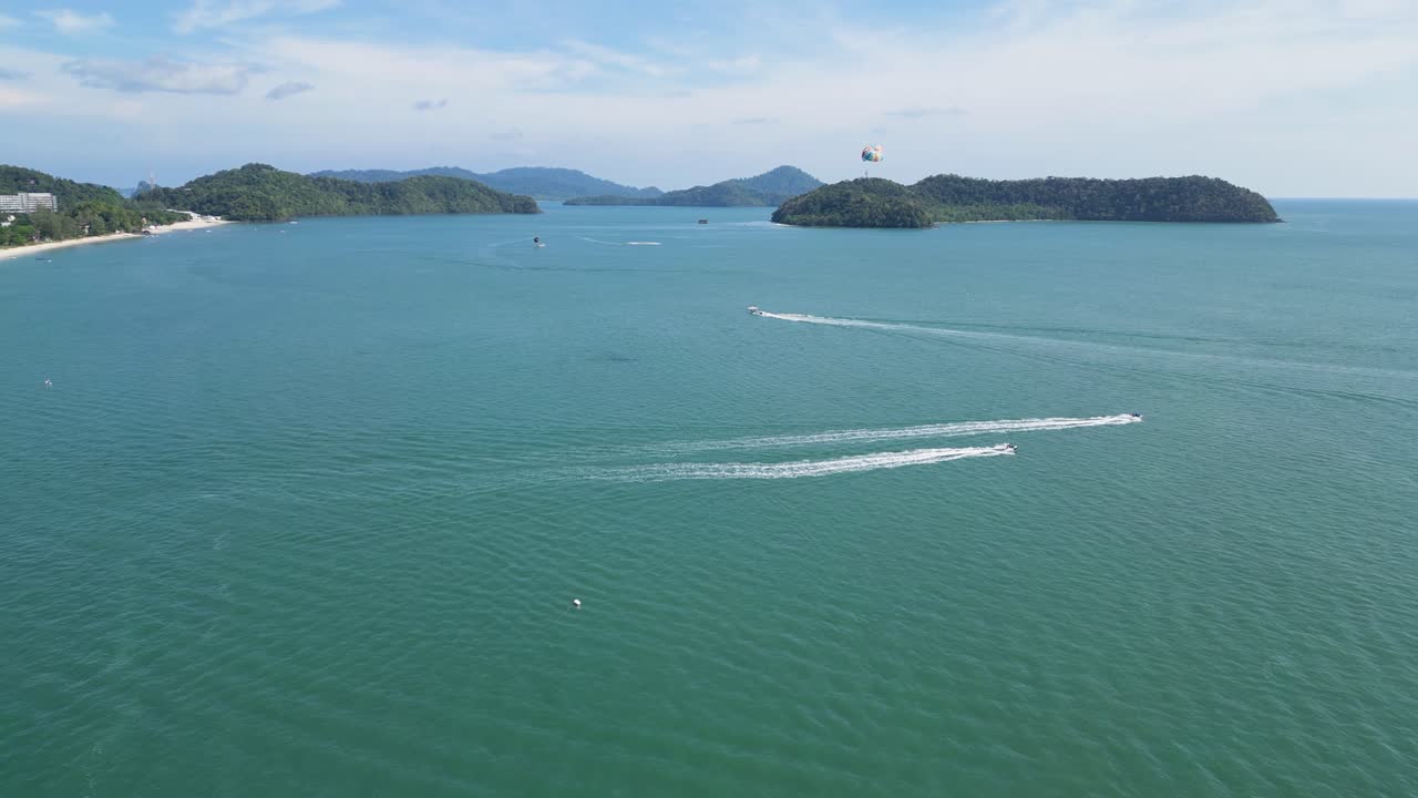 말레이시아 랭카위 (langkawi) 에서 바다, 배, 그리고 멀리 있는 패러세일러가 있는 열대 해안선의 아름다움을 포착하는 공중 촬영