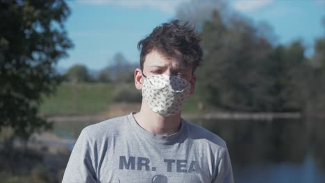 young man puts on homemade white corona virus cotton mask medium shot