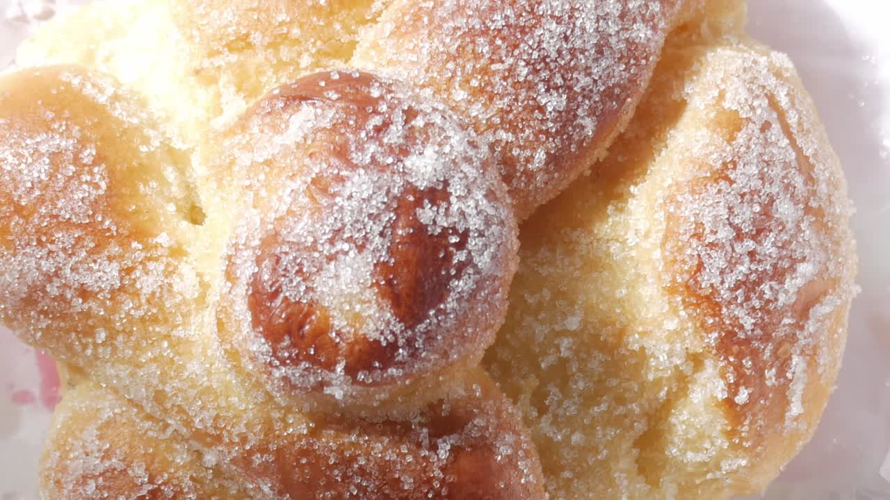 Tilt up closeup of sugary sweet bread, Pan de Muerto. Bone-shaped decoration on bun top. Typical Mexican sweet on All Saints Day, Dia de los Muertos.