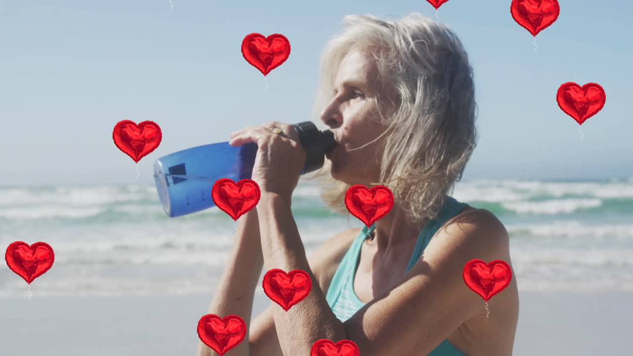 animación de globos de corazón rojo que se elevan sobre la mujer bebiendo agua en la playa
