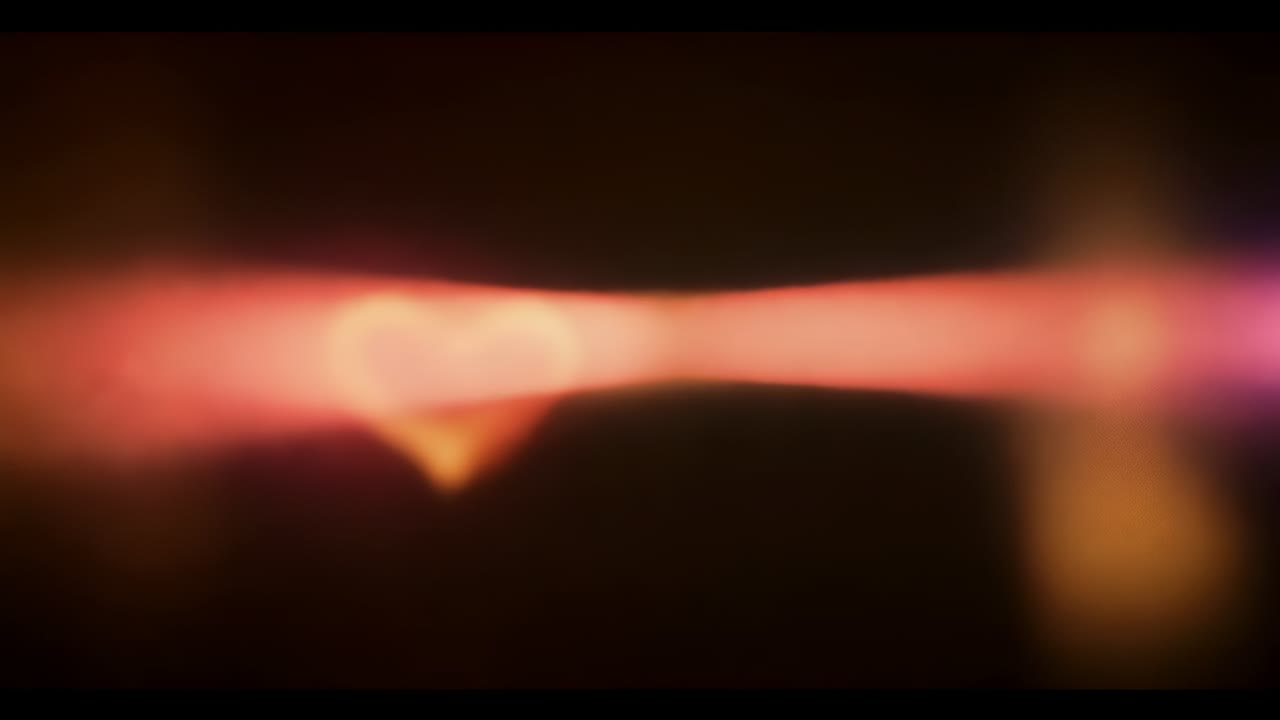 Pulsing heart glow starting with faint light streak in dark frame, forming triple soft right flare