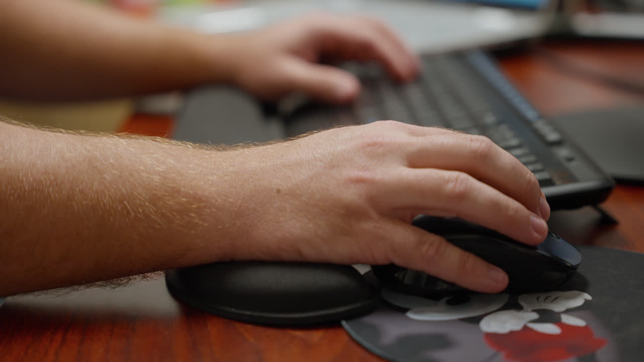 Hands using a keyboard and mouse at computer desk working in office